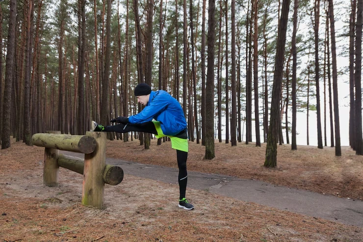 person-stretching-leg-on-wooden-bar-in-forest