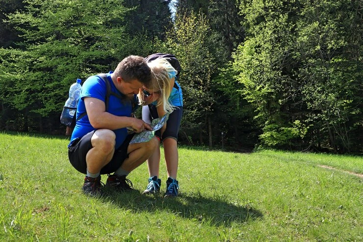 couple-studying-map-while-hiking-in-sunny-forest